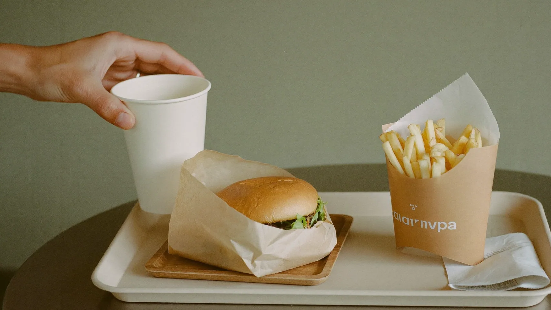Bandeja de combo armándose en el mostrador: hamburguesa, papas y bebida