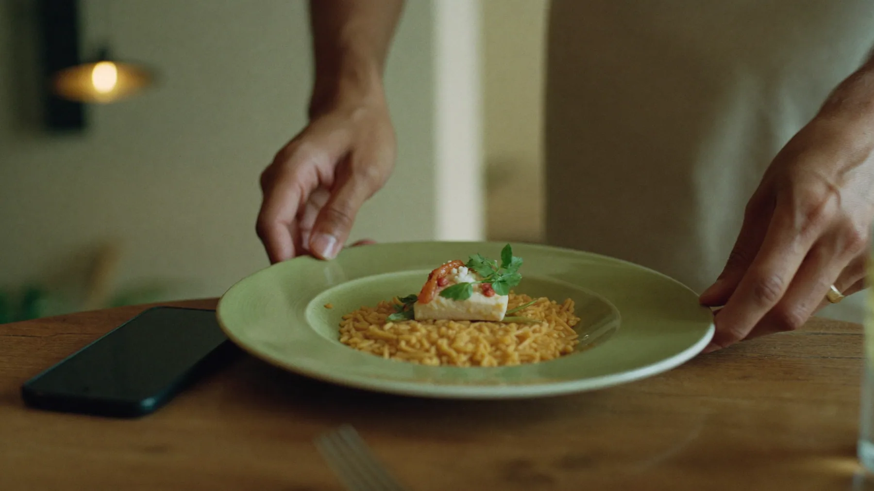Plato destacado de la carta recién servido en la mesa, con el celular del cliente al lado